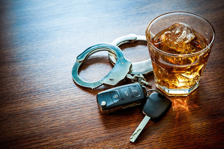 Alcoholic beverage next to car keys and handcuffs